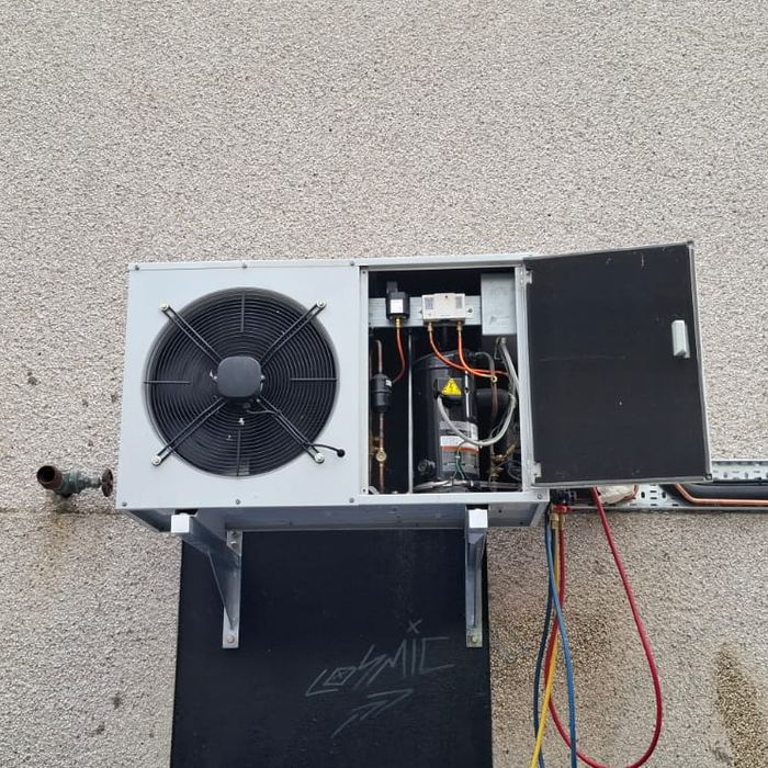 Commercial condensing unit opened up with refrigeration gauges connected